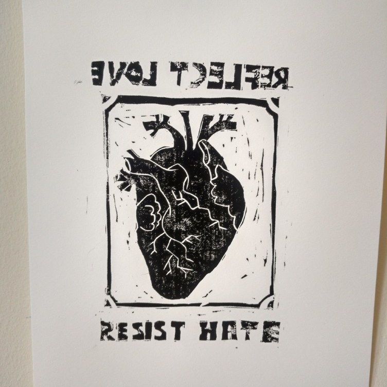 a heart reflected backwards with the words reflect love backwards above the heart and resist hate forwards beneath the heart
